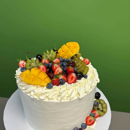 Gâteau blanc garni de fruits frais — fraises, kiwis, mangue et bleuets — de la Pâtisserie Saveurs du Monde